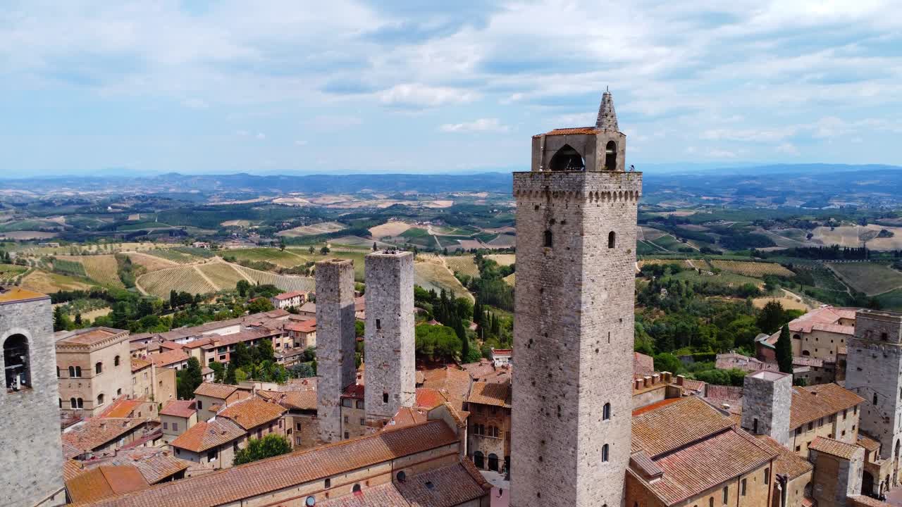 Cinematic drone shot of San Gimignano’s famous skyline with its medieval towers and sweeping Tuscan hills in golden daylight.