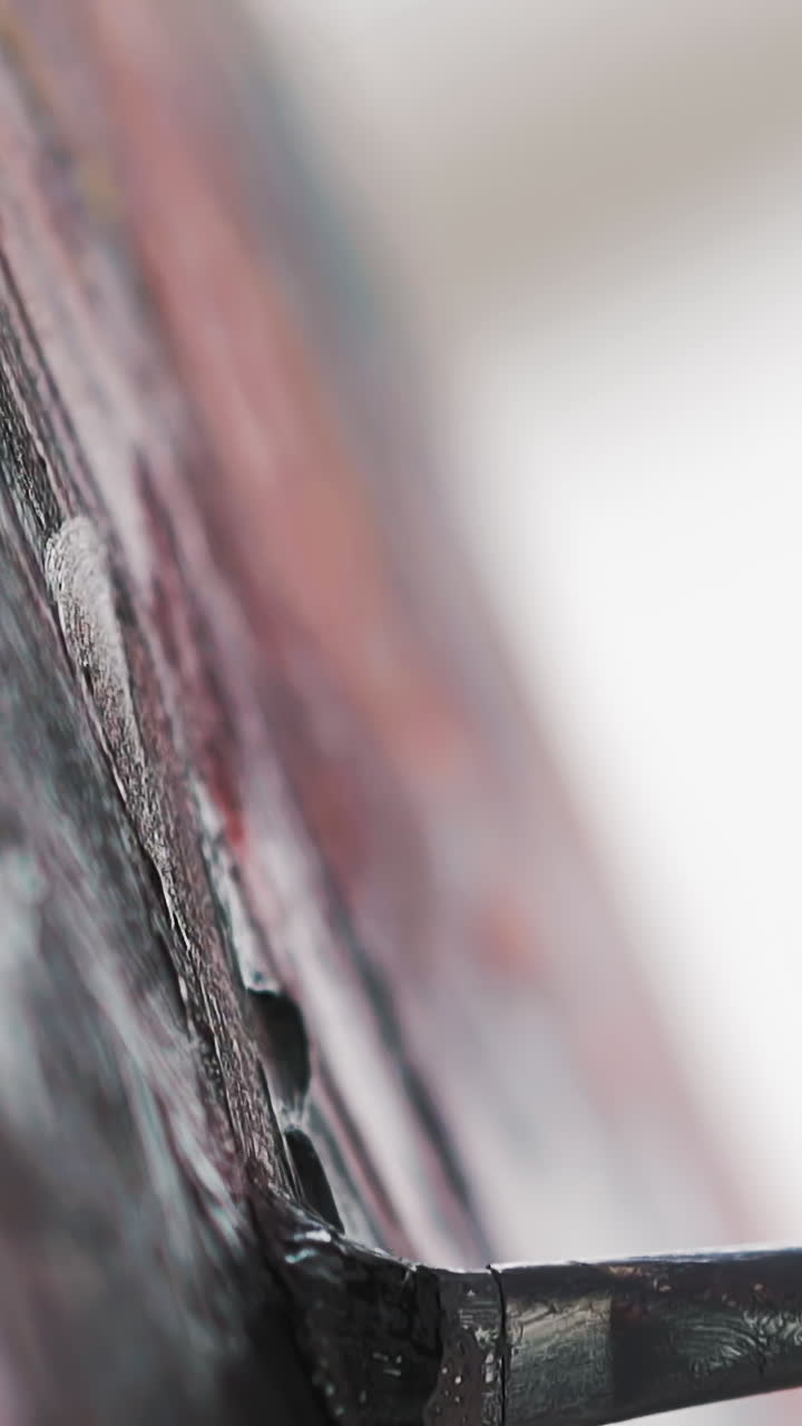 Skilled artist draws picture applying dark paint with paintbrush on canvas at art lesson in studio extreme closeup slow motion vertical shot