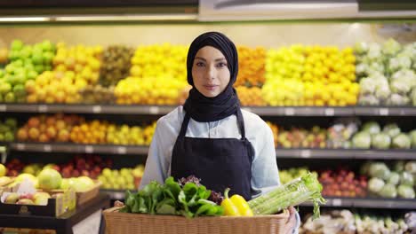 portrait of a woman in hijab standing with basket of fresh vegetables in the supermarket