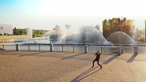 modern boy dancer is dancing in the street. urban lifestyle. hip-hop generation. boy's emotional moves on the video. paving stones and young man at fontain background. aerial view. young handsome professional dancer boy.