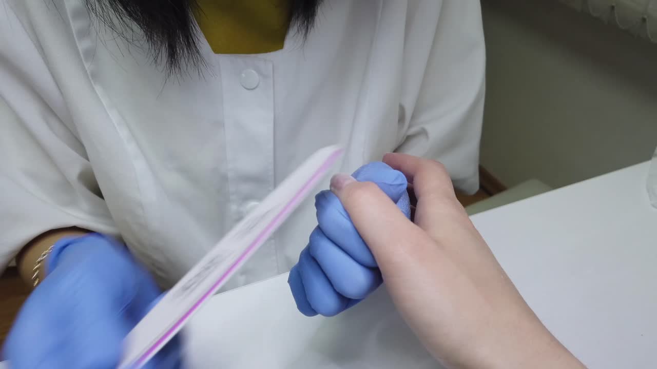 Nail master doing a woman's manicure at a salon