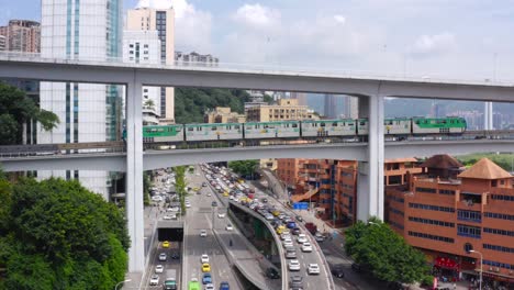 chongqing city china above ground green line rail passes above traffic jam on highway below, aerial