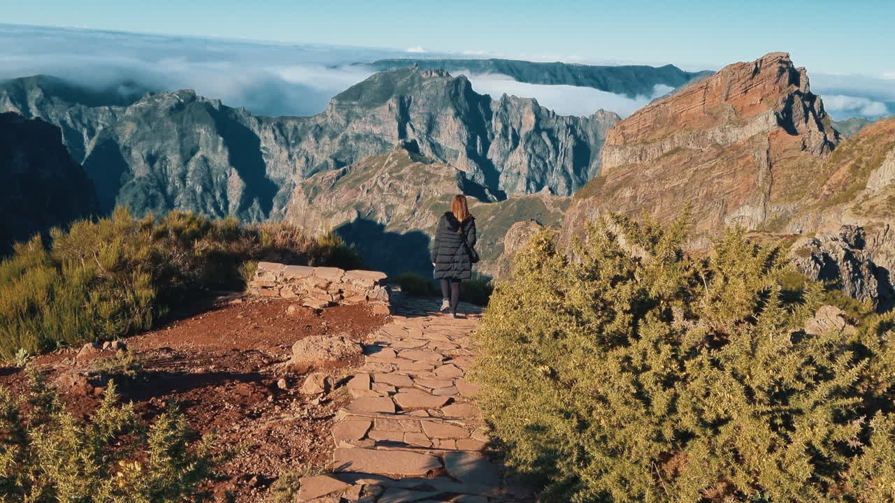 Female traveler walking on a trail in the mountains of Pico do Arieiro, Madeira, Portugal