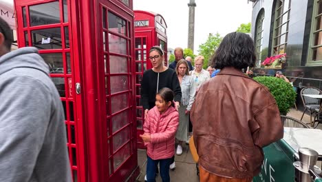 people walking past a restaurant and phone booth