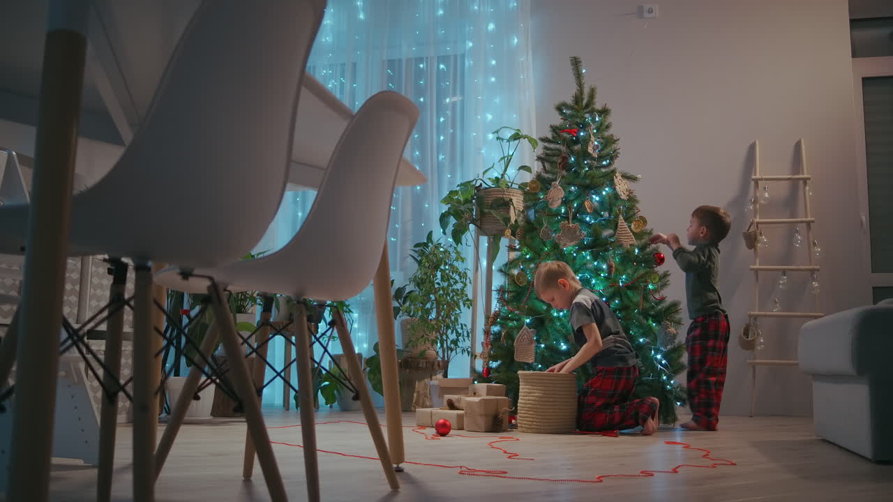 niños de 5-8 años decorando juguetes de árbol de navidad en el árbol de navidad en la víspera de navidad. imágenes de alta calidad 4k