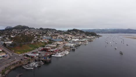 Wide-panning-aerial-shot-of-the-Embarcadero-and-harbor-in-Morro-Bay,-California