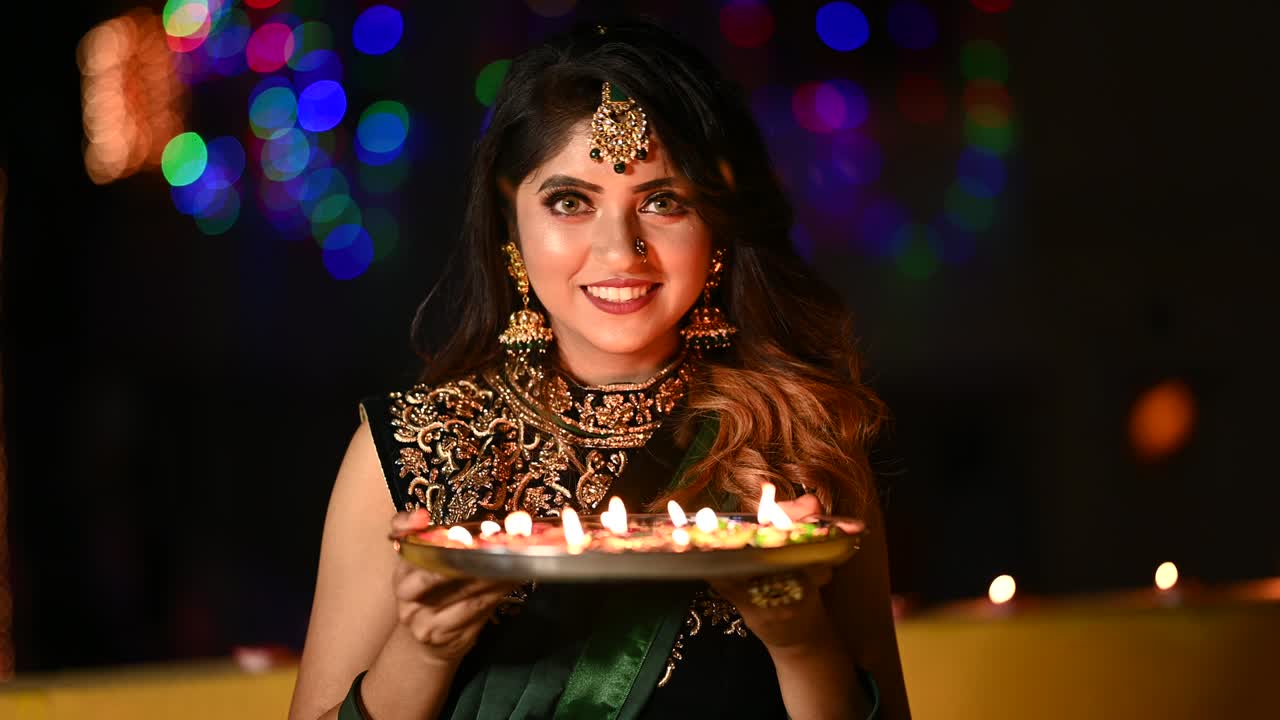 una joven hermosa encendiendo una lámpara de aceite en ropa tradicional con ocasión de diwali.