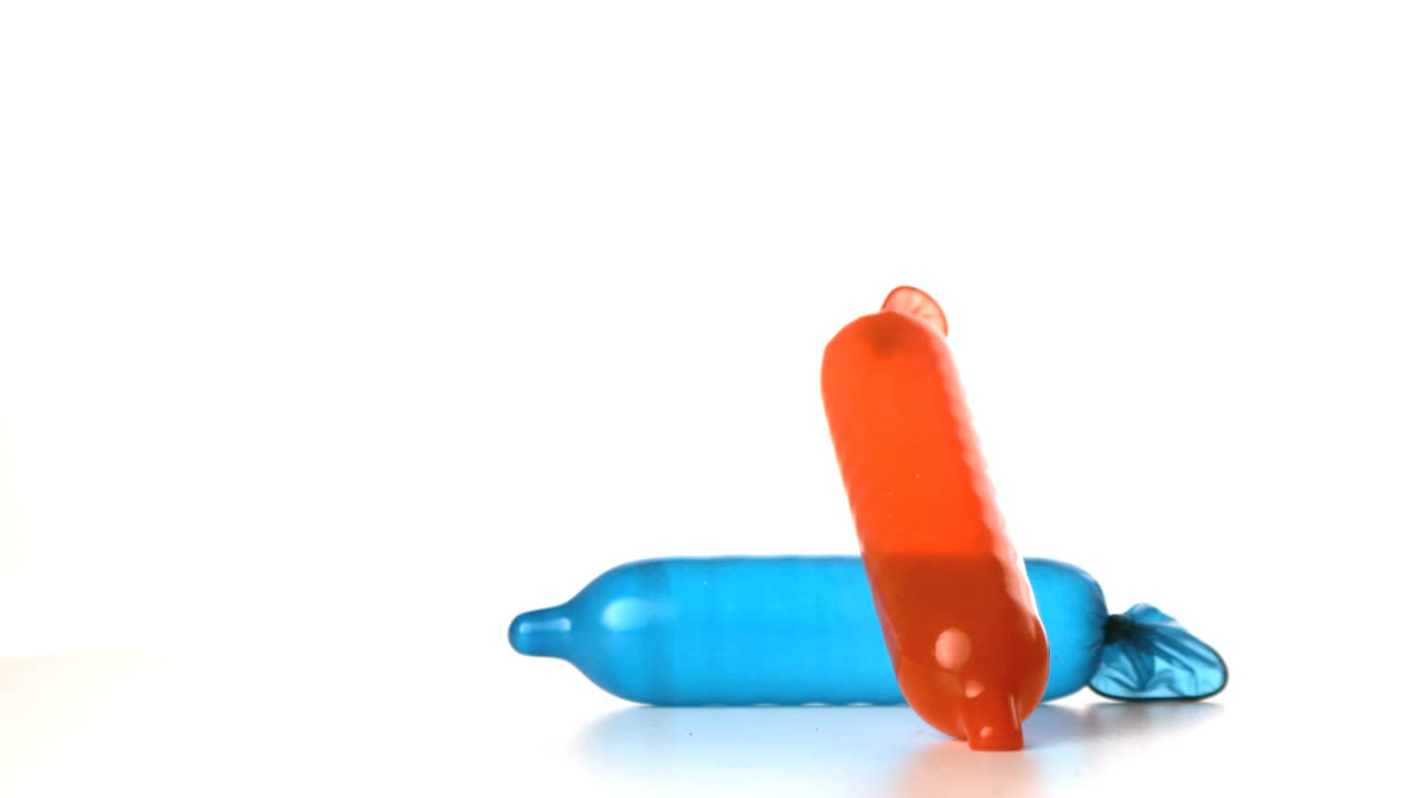 un condón explotado cayendo sobre otro sobre un fondo blanco