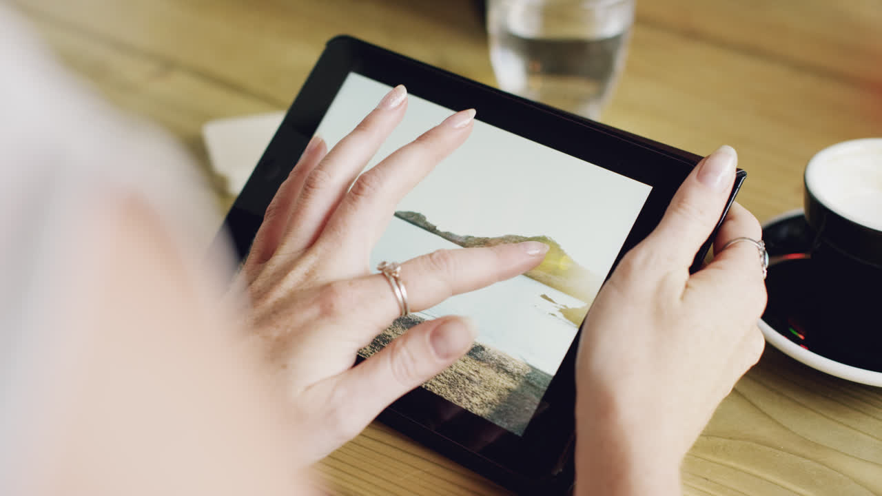 Close up hands using digital tablet touchscreen device ipad in cafe