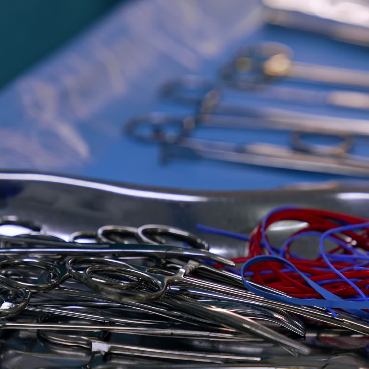 Many forceps on the metal tray. Surgical instruments prepared for the surgery. Close up. Blurred backdrop
