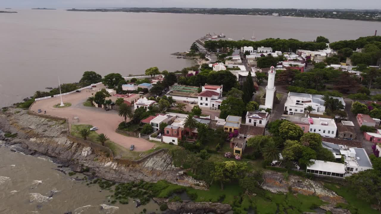 toma de órbita aérea del faro y la costa de la ciudad de colonia del sacramento en uruguay durante el día nublado oscuro