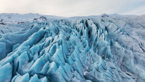 vista aérea del paisaje sobre las formaciones de hielo texturizadas de un glaciar en islandia, al anochecer