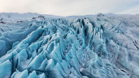 aerial landscape view over textured ice formations of a glacier in iceland, at dusk