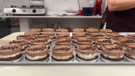 time lapse of a female pastry chef writing names in her chocolate cakes over a marble table inside her traditional workshop. 4k