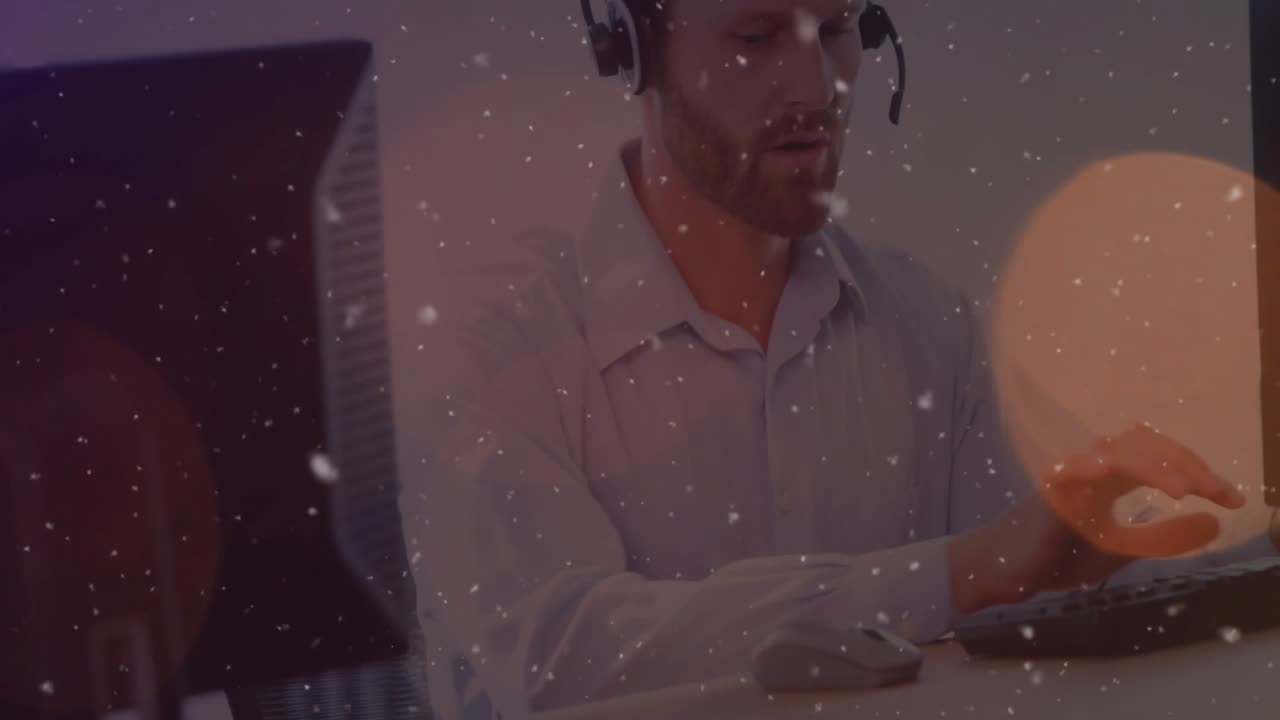 Woman typing at desk monitor, man donning headset then typing while speaking for business call