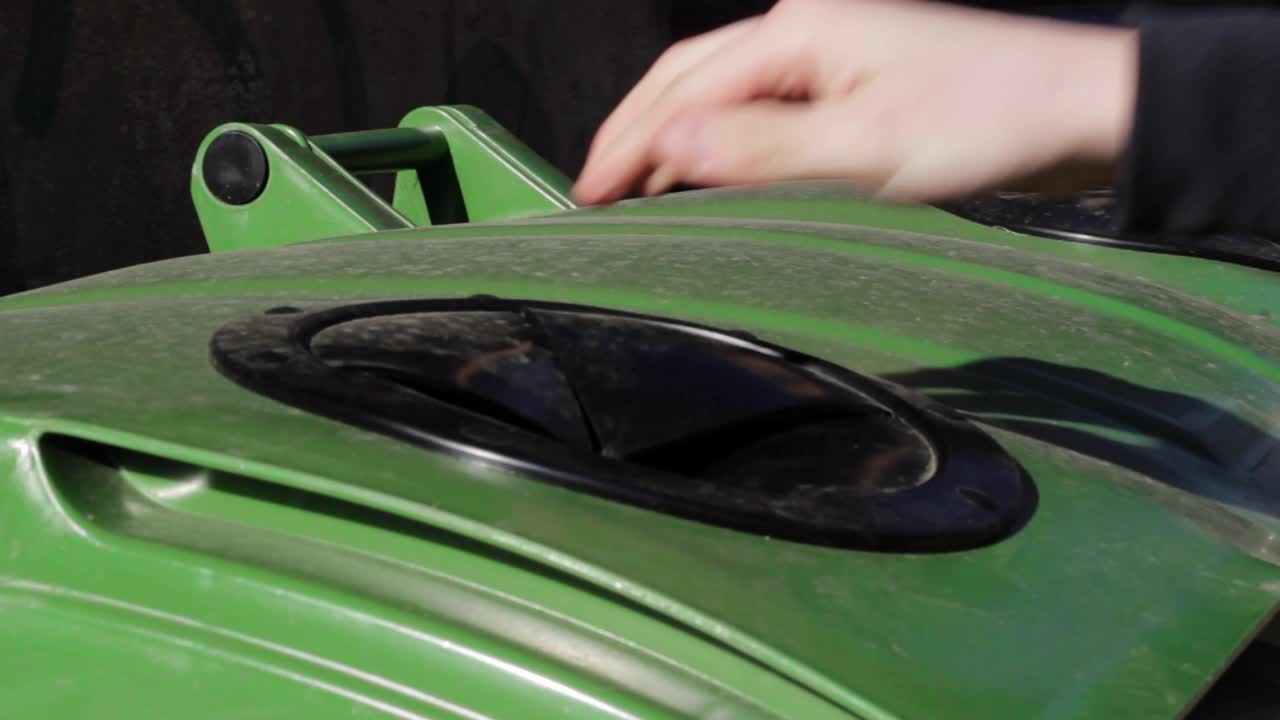 tirando una botella de vidrio reciclado con un contenedor con solapas, cerrado