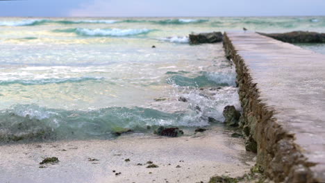 Turquoise-waves-crashing-against-concrete-walkway