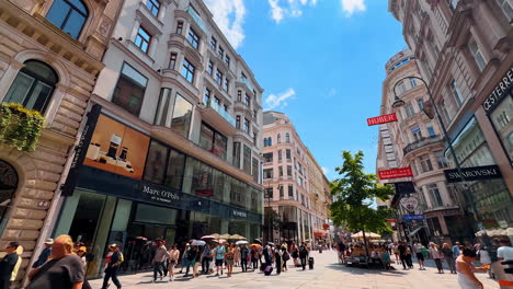 vienna, austria - june 9, 2025: modern shops with large showcases in the old historical buildings. tourists and locals walk by the beautiful pedestrian street in old town of vienna, austria