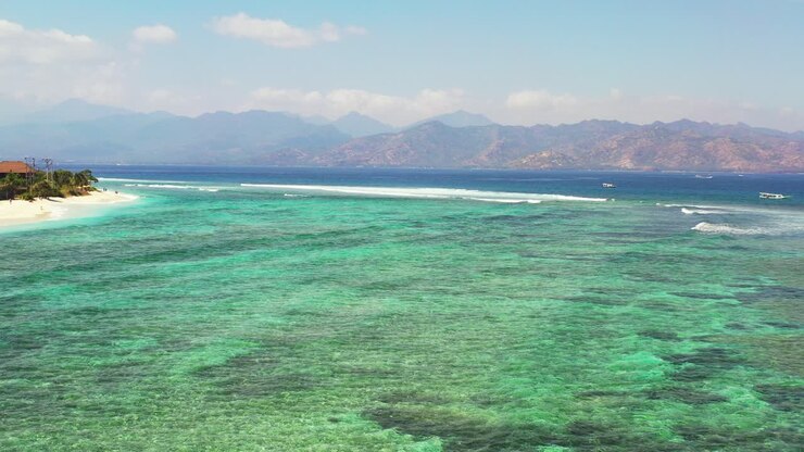 Beautiful patterns of coral reefs and rocks underwater on turquoise lagoon around white sandy beach of tropical island, Bali