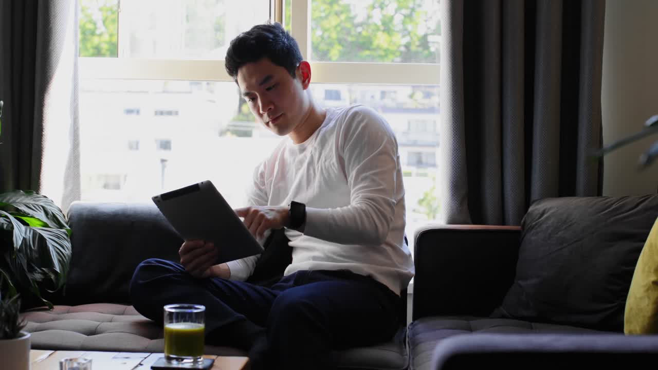 소파에 앉아 디지털 태블릿 4k를 사용하는 남자