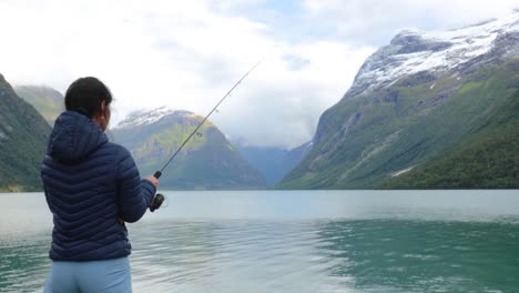 mujer pescando en una caña de pescar girando en noruega.