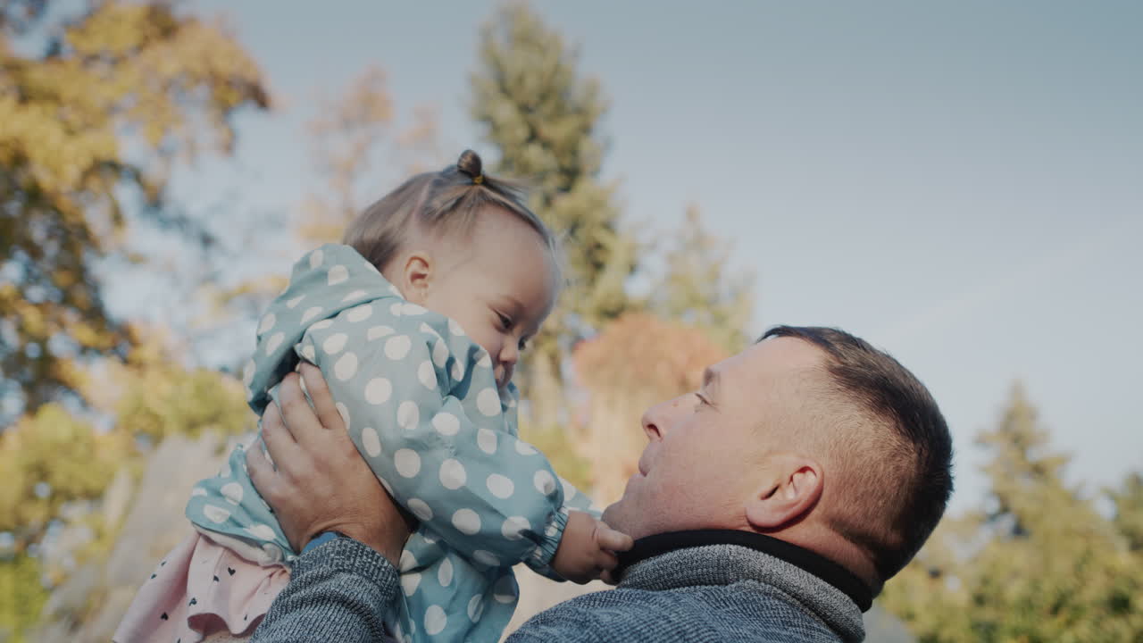 Padre felice che gioca con la sua figlioletta nel parco, si divertono insieme.