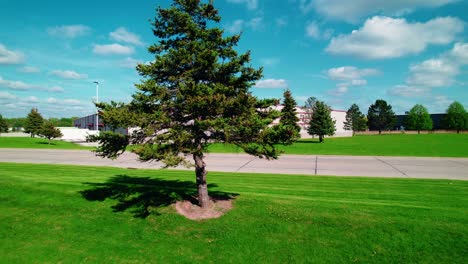high-angle drone footage showcases a green bay distribution warehouse by a pine-lined road and manicured lawns under clear blue skies.