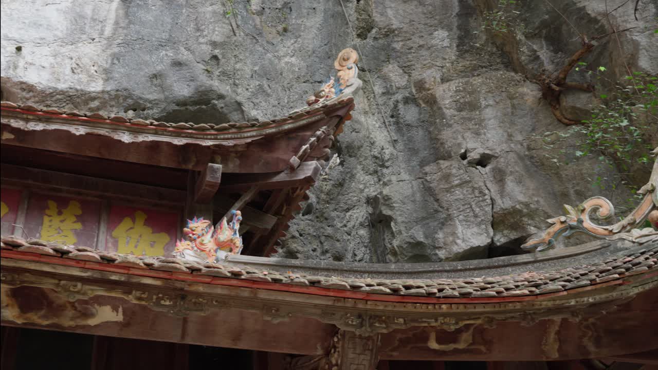 Detail temple roof outside big rock cave, Bich Dong, panning shot