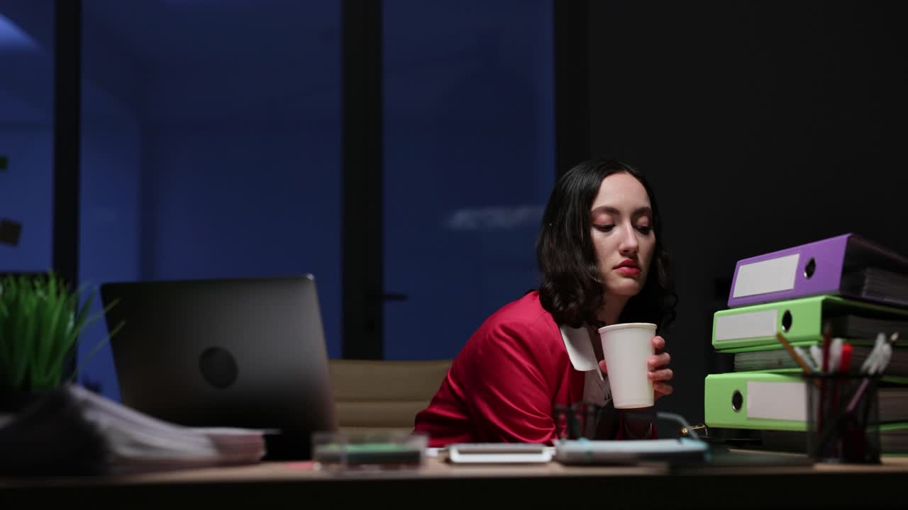 Woman at desk at night with laptop and documents