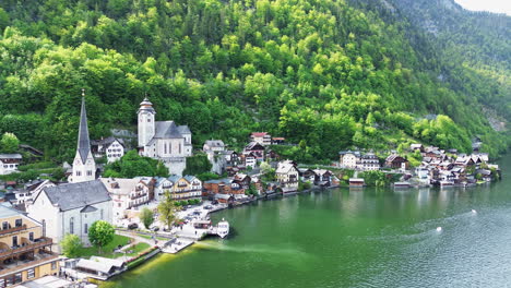 hallstatt town along the lake in daytime with verdant forest in the mountain in austria. - aerial shot