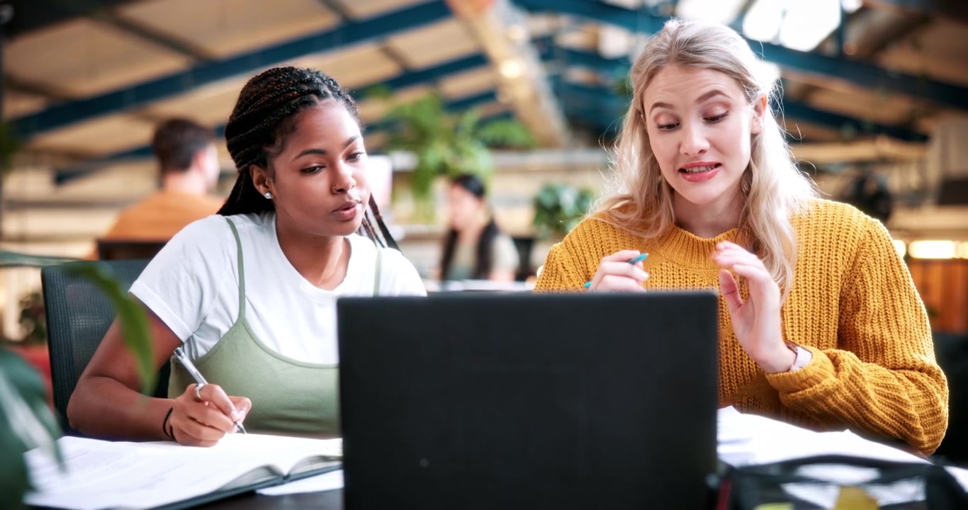 Two Young Women Collaborating on a Project in a Modern Office