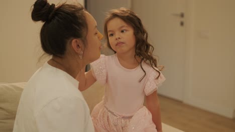 little girl applying makeup to her pregnant mother at home