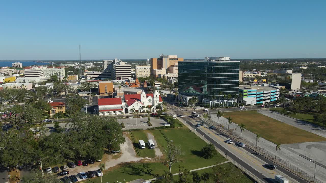 Aerial drone view of downtown Bradenton Florida showcasing buildings, and surrounding cityscape under clear blue skies. Crane Up Left E