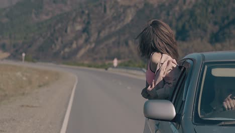 girl-sits-on-car-window-and-expresses-emotions-of-happiness