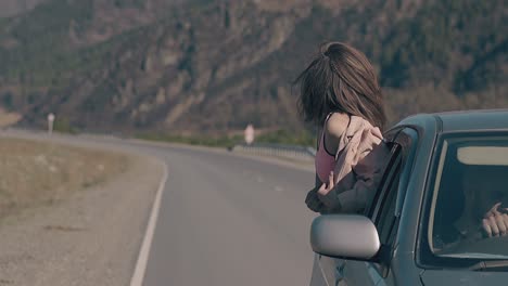 소녀는 자동차 창문에 앉아서 행복의 감정을 표현합니다.
