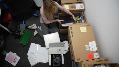 mujer joven empacando cosas en cajas para un movimiento en su habitación desordenada