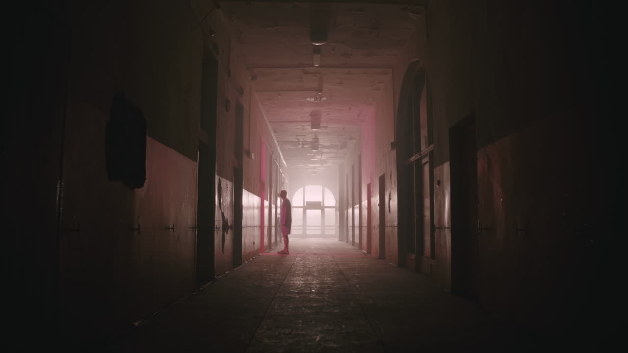 A bald man walks on the empty hospital corridor at night