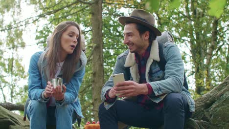 excursionistas bebiendo café y usando el teléfono móvil