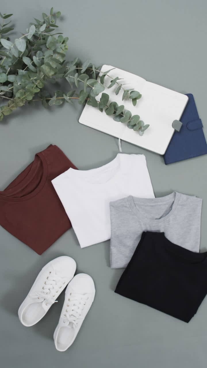 Vertical video of flat lay of t shirts and shoes with copy space on gray background