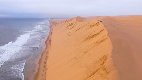 Impresionante-Toma-Aérea-Sobre-Las-Vastas-Dunas-De-Arena-Del-Desierto-De-Namib-A-Lo-Largo-De-La-Costa-De-Los-Esqueletos-De-Namibia-Termina-En-Safari-Van-1