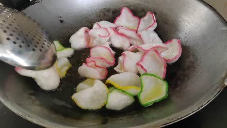 keropok sayur frying in a wok, expanding and crisping in hot oil. a favorite malaysian snack.
