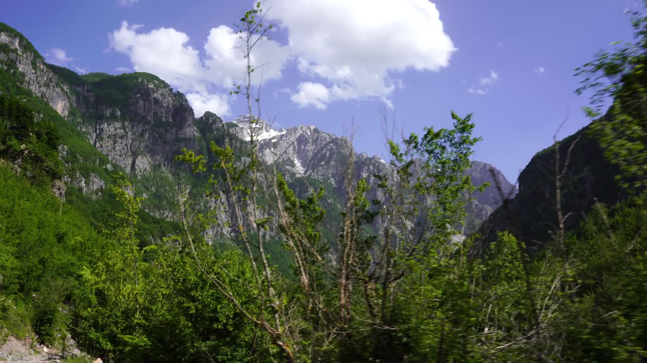 senderismo en el hermoso valle de theth, a través de una exuberante vegetación, hacia las altas montañas por la mañana