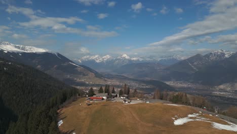 Aerial-drone-flying-over-houses-on-a-mountain-with-fields-and-trees-besides