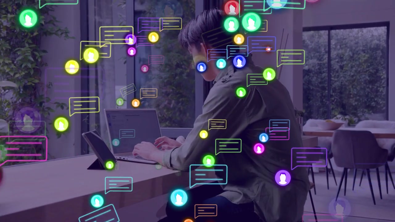Adult male receiving floating messages, turning to counter, sitting, typing on laptop to respond