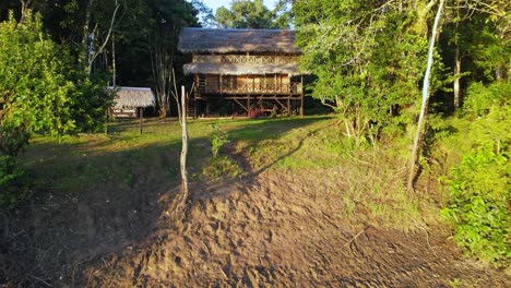 Luftaufnahme,-Die-Sich-Vorwärts-Bewegt,-Eine-Holzhütte-Am-Ufer-Des-Amazonas-In-Kolumbien,-Ein-Hoher-Baum-Und-Ein-Heller-Sonniger-Tag-Im-Hintergrund