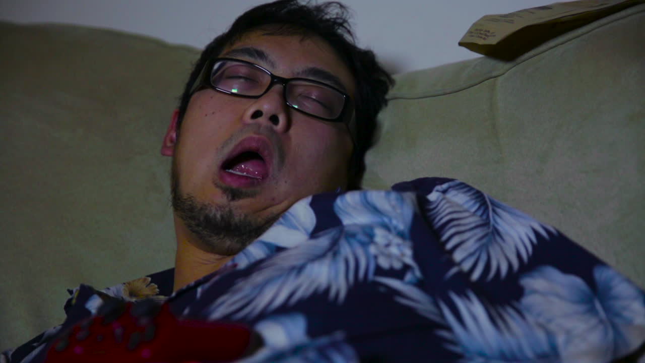 입을 벌리고 소파에서 잠든 젊은 남자