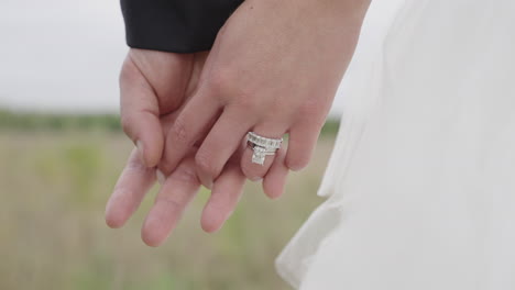 bride and groom holdings hands on wedding day, close up