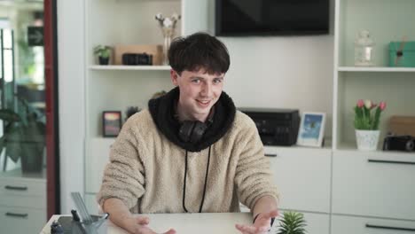 the young boy, a high school student, is giving an interview on camera. he emotionally narrates something to the camera and gestures lightly with his hands. the youtube blogger is speaking on camera.