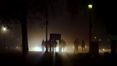 people waking on a dark street with car back lighting them, rainy day, glow, haze, fog, niagara falls, canada