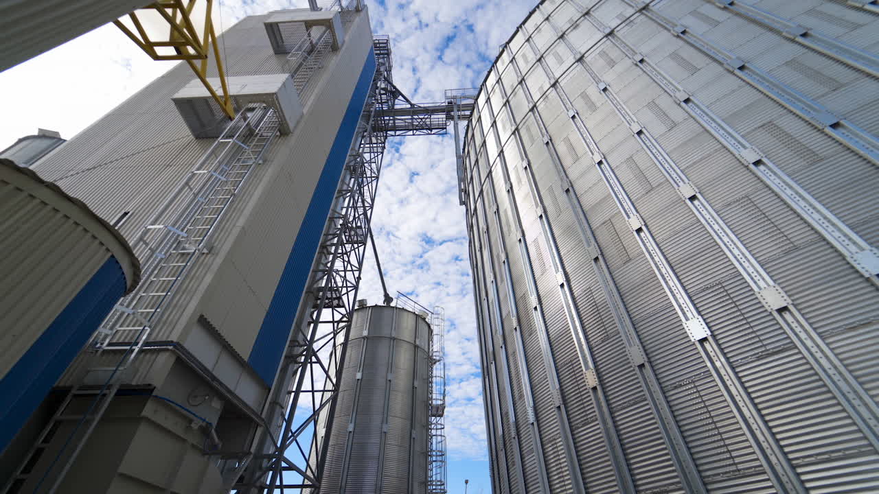 Modern industry for agribusiness. Large silver silos at sunlight. Grain elevators on sky background. Storage tanks outdoors. Close-up.